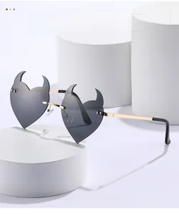 Detail of heart-shaped sunglasses with devil horns and gold metal frame on a white stand