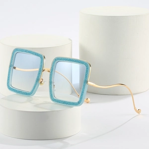 Blue glitter square sunglasses with wavy gold metal temples on geometric display stands