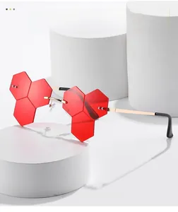 Detail of red geometric rimless sunglasses with gold metal frame and triple hexagon lenses