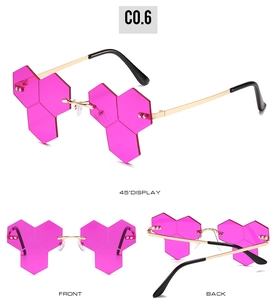 Detail view showing frameless hexagonal rose pink lenses and gold metal frame of sunglasses