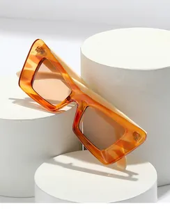 Gros plan de lunettes de soleil orange rectangulaires sur socles blancs avec détails monture