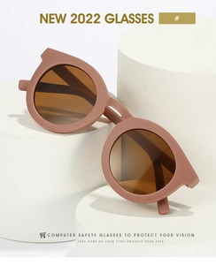 Detail view of vintage matte orange round sunglasses on white stands with soft lighting