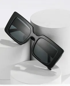 Detail of black oversized square sunglasses on white geometric display stands