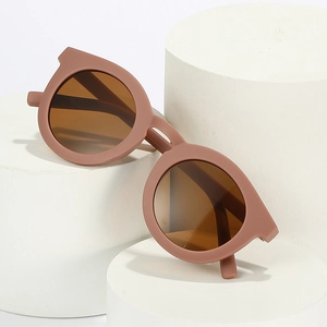 Retro round matte brown children sunglasses with UV protection on a minimalist stand