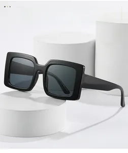 Detailed view of oversized square sunglasses on a white pedestal with premium black finish
