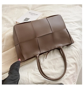 Detail view of deep brown woven leather tote with intricate Intrecciato craftsmanship