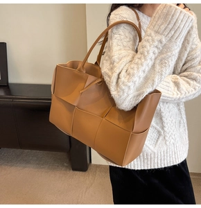 Detail of caramel woven leather tote bag texture and large capacity shoulder strap design