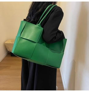 Detail shot of the large green woven leather tote bag carried on a shoulder for daily use