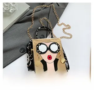 Détail du sac boîte doré avec visage de femme cartoon et foulard sur la poignée