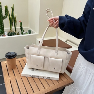 Detail of off-white tote bag with double front flap pockets and metallic buckles