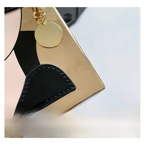Détail du sac à main miroir doré avec bordure noire et chaîne métallique élégante