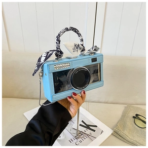 Detail of camera-shaped light blue jelly crossbody bag with black feathers and floral scarf
