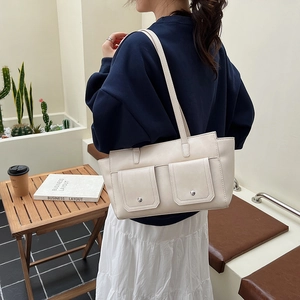 Detail of cream white leather shoulder bag with metallic rivets and utility pockets
