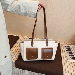 Detail of contrast color tote bag with dual front pockets and silver rivet accents