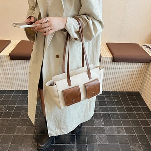 Detail of a beige and brown contrast crossbody bag with double front flap pockets