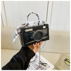 Detail of camera-shaped crossbody bag with rhinestone lens and silk scarf handle