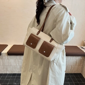 Detail view of cream and brown crossbody bag featuring silver studs and contrast pockets