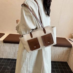 Detailed view of crossbody bag showing beige leather material with brown contrast pockets