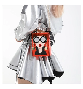Détail du sac boîte rouge avec visage cartoon et foulard, bandoulière chaîne vue de côté