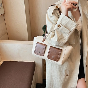 Detail of retro contrast shoulder bag featuring twin brown flap pockets and silver buckles