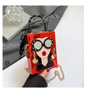 Sac boîte rouge avec visage cartoon et poignée en soie sur une table de mode