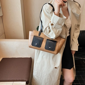 Detail of crossbody bag featuring contrast dual front pockets and silver buckle closures