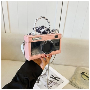 Pink camera-shaped crossbody bag with transparent window and black-white patterned scarf