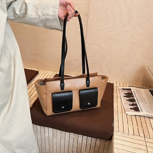 Detail of contrast color tote bag featuring front flap pockets and metallic stud accents