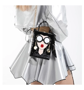 Détail du sac boîte en cuir verni noir avec visage de dessin animé et chaîne dorée