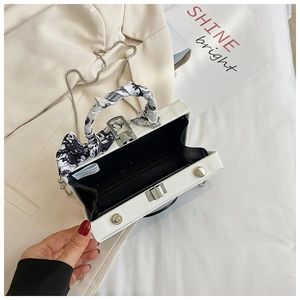 Detail view of white PVC box bag with inner lining and silk scarf wrapped handle