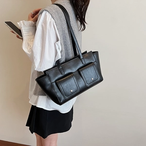 Detail of black leather tote bag with silver metal rivets and flap pockets