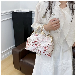 Detailed close-up of floral embroidery and pearl accents on a vintage cheongsam handbag