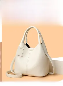 Detail of off-white lychee grain leather bucket bag with bear pendant and smooth texture