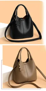 Detail view of lychee grain leather bucket bags in black and camel with bear charms