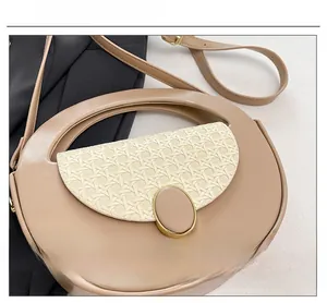 Detail of a minimalist half-moon crossbody bag with woven texture and gold metal buckle