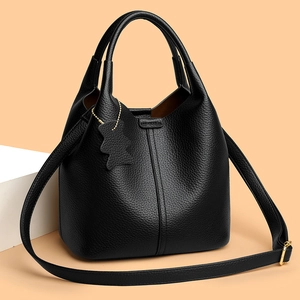 Detailed macro view of black lychee grain leather bucket bag with cute bear charm and gold hardware