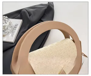 Detail of woven texture flap and rigid circular handle on a beige crossbody bag