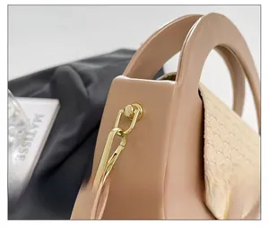 Detail shot of premium gold-toned metal hooks on a minimalist beige leather shoulder bag