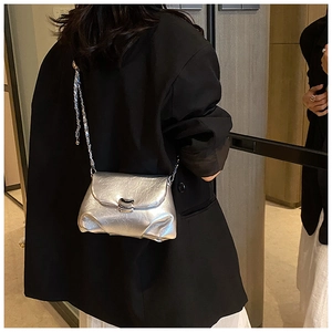 Borsa a tracolla argento a pieghe con catena indossata sopra una giacca nera da dietro
