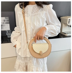 Detail of apricot round handbag showing woven texture, gold buckle, and adjustable strap