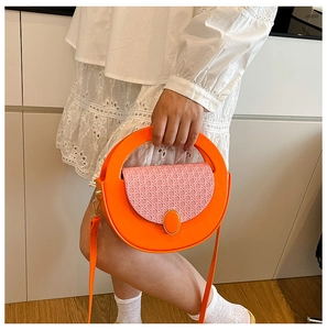 Detail of round orange crossbody bag with pink woven texture flap and metallic clasp