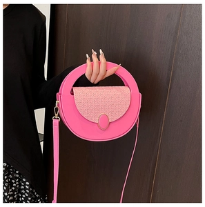 Detail of hot pink handbag with crossbody strap and textured woven flap design