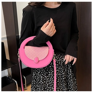 Detail of pink crossbody bag with woven texture and gemstone buckle worn by model
