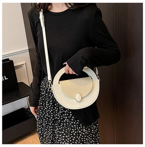 Detail of a round cream shoulder bag featuring a beige woven flap and gold metal clasp