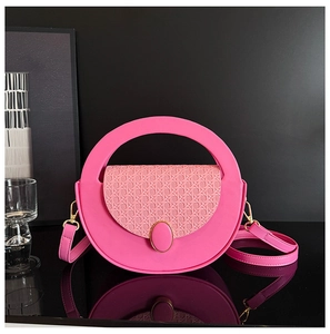 Close-up of a pink crossbody bag with woven texture and gold clasp on a reflective surface