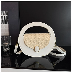 Detail of white round leather bag with woven flap and circular metal decorative buckle