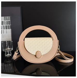 Detail of minimalist beige handbag with woven flap and circular cutout handle