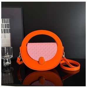 Detail of a bright orange leather bag with pink woven flap and golden buckle