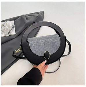 Detail of round black handbag with grey textured flap and gold buckle fastener