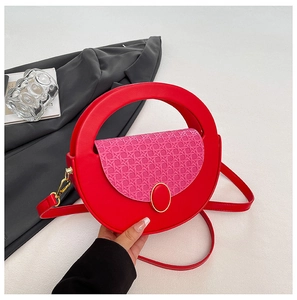 Detail of round red leather crossbody bag with pink woven flap and gold oval clasp